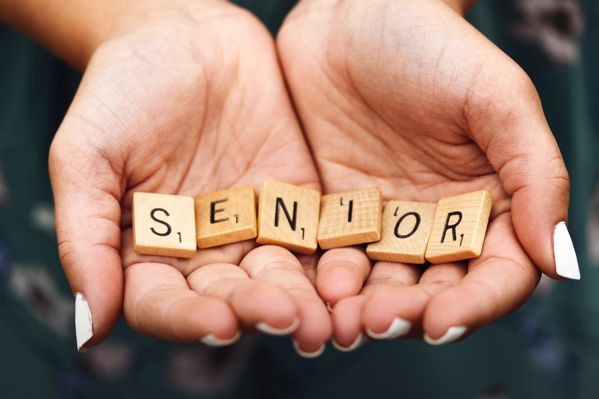 Foto di due mani che tengono alcune tessere con scritto senior
