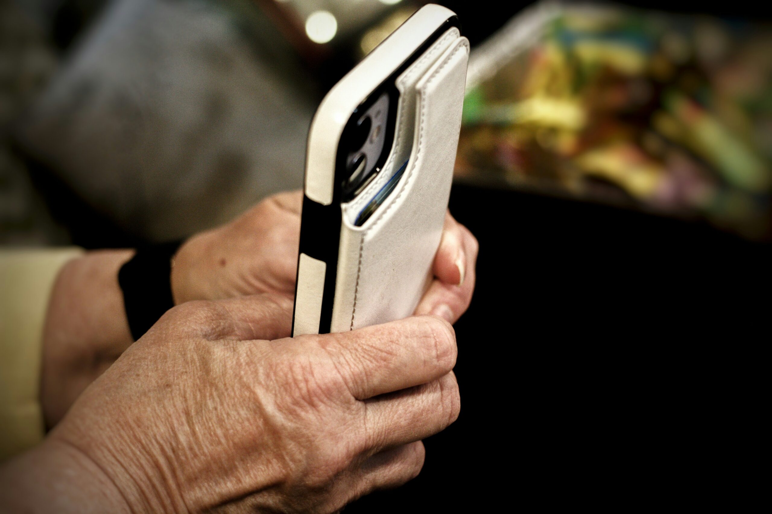 Foto delle mani di una persona anziana che reggono uno smartphone