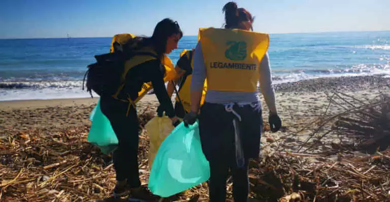 Foto di due ragazze che puliscono una spiaggia